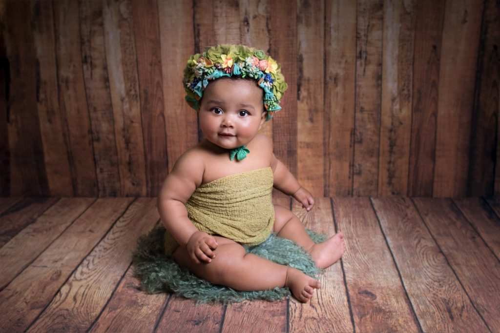 Séance bébé 6/9mois chez Ophélie Bajeux photographie. Petite fille avec un gros bonnet fleuris dans les tons verts.