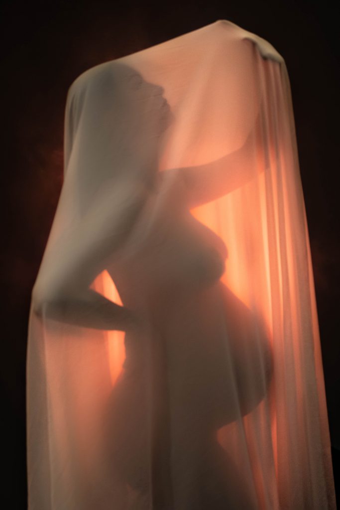 Séance photo grossesse au studio photo Ophélie Bajeux Photographie dans un style artistique avec un voile.